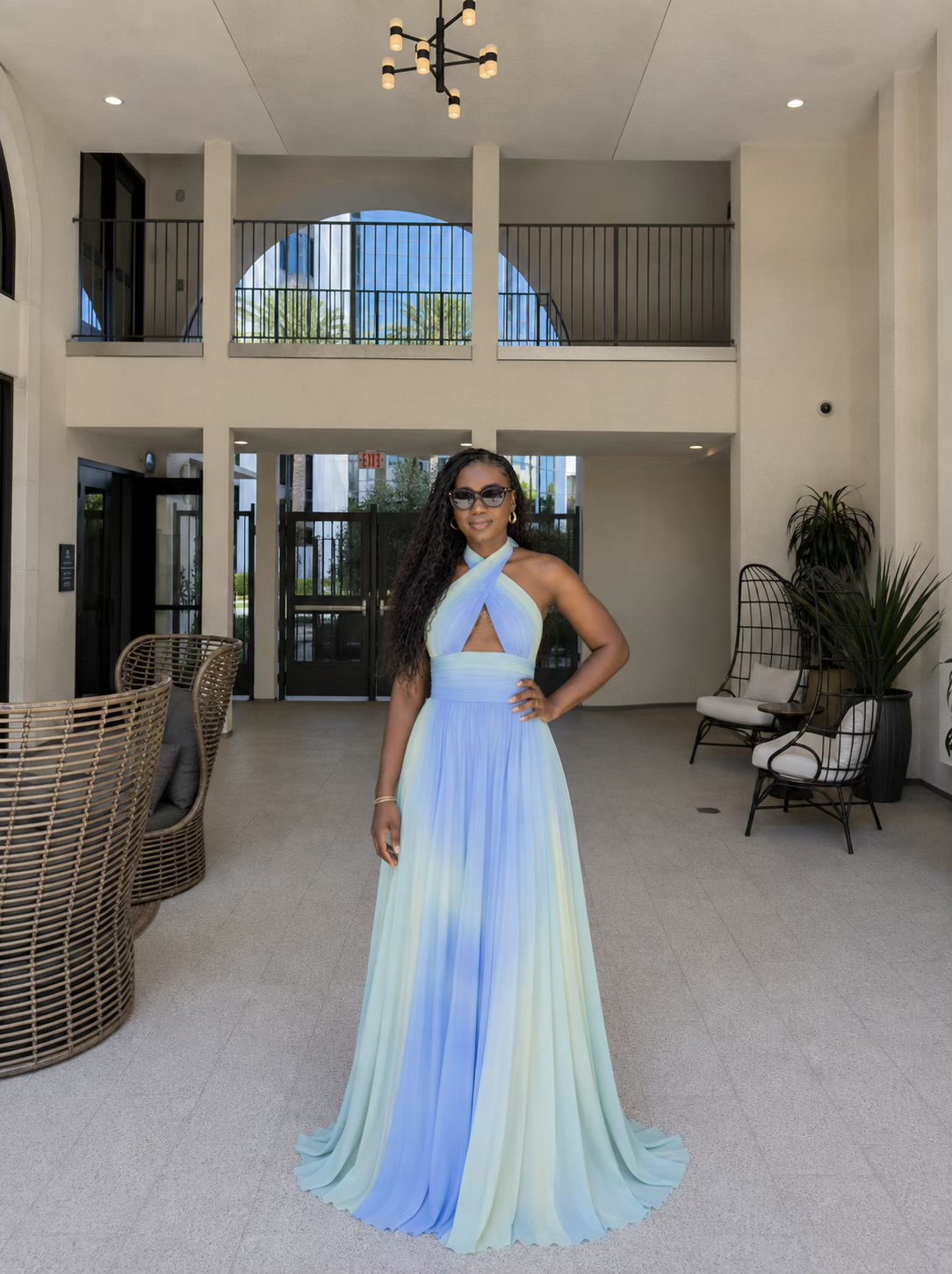 Julie Don in a pastel ombré gown in a sunlit courtyard